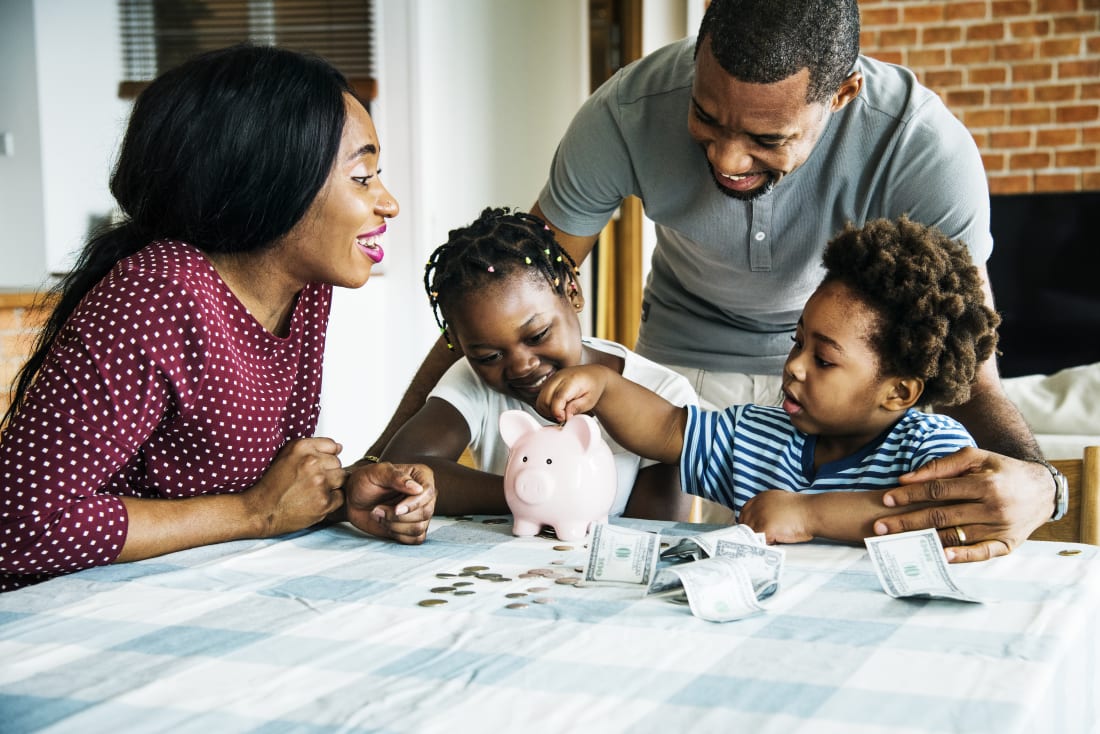 Family with two kids putting money into piggy bank.
