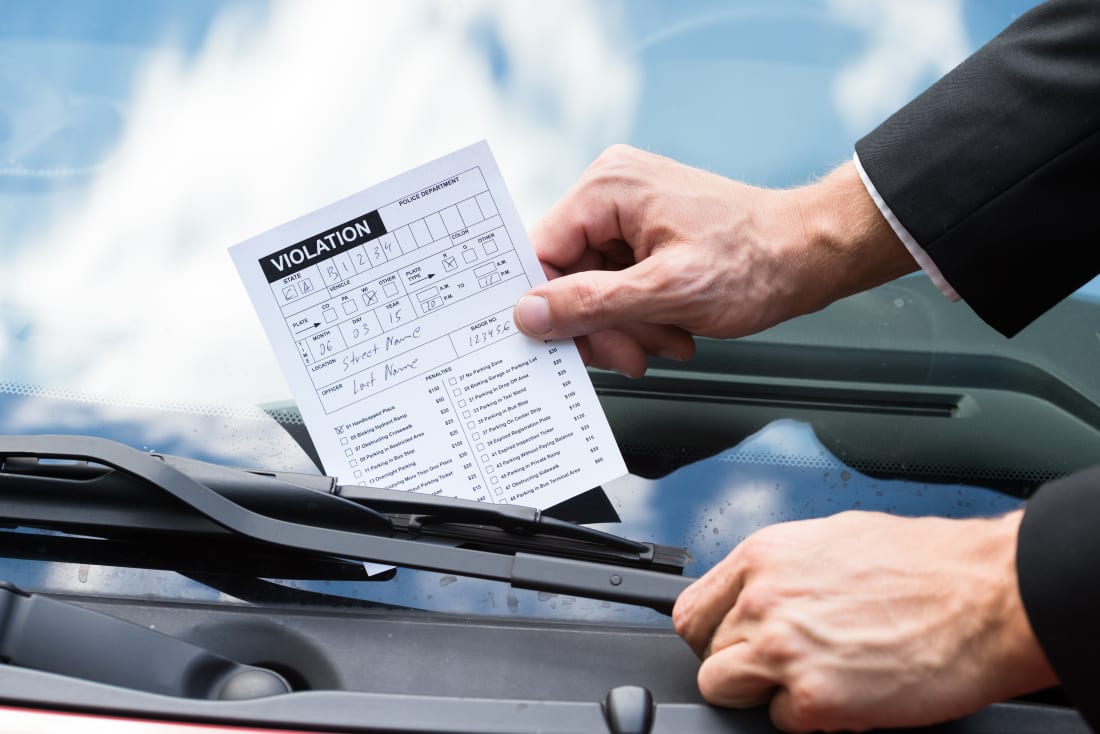 Close-up Of A Man Taking Parking Ticket On Car's Windshield