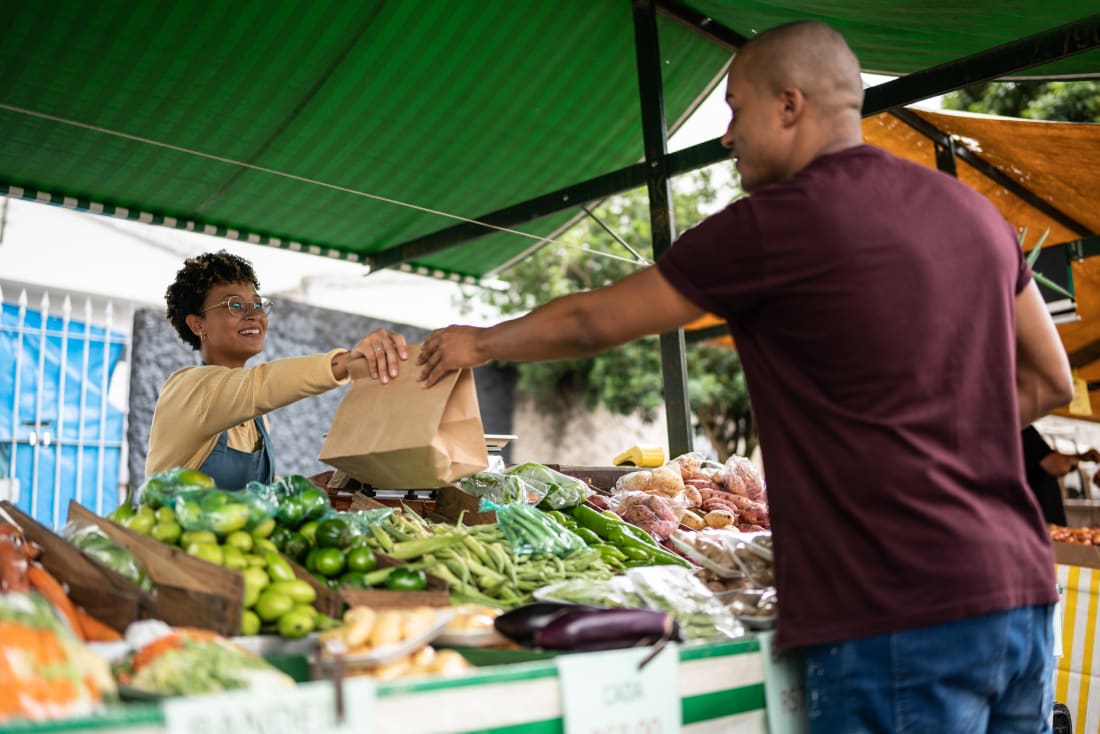 man buying produce from lady at farmers market
