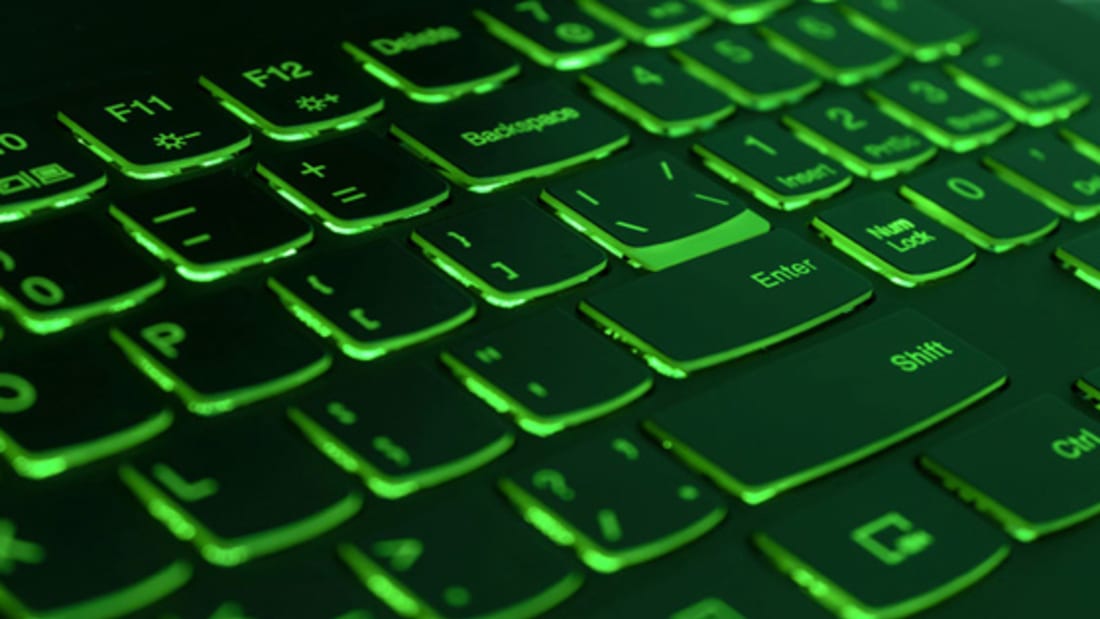 Green backlit laptop keyboard, hacking and blockchain concept