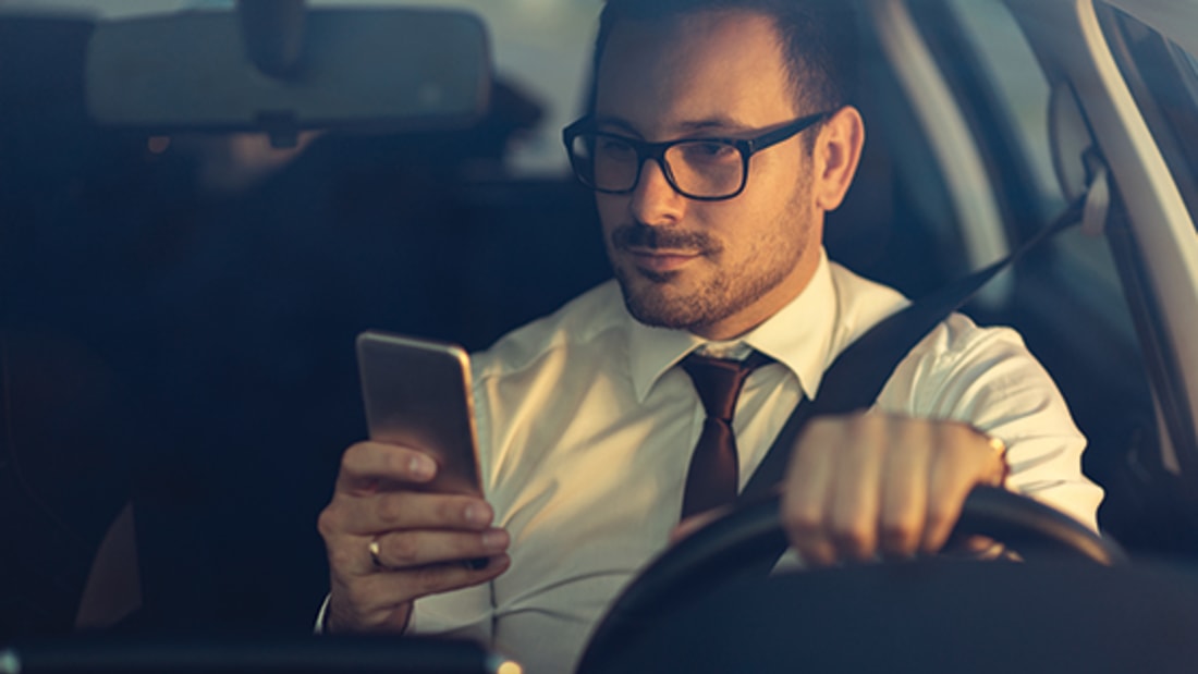 Businessman using a phone while driving a car