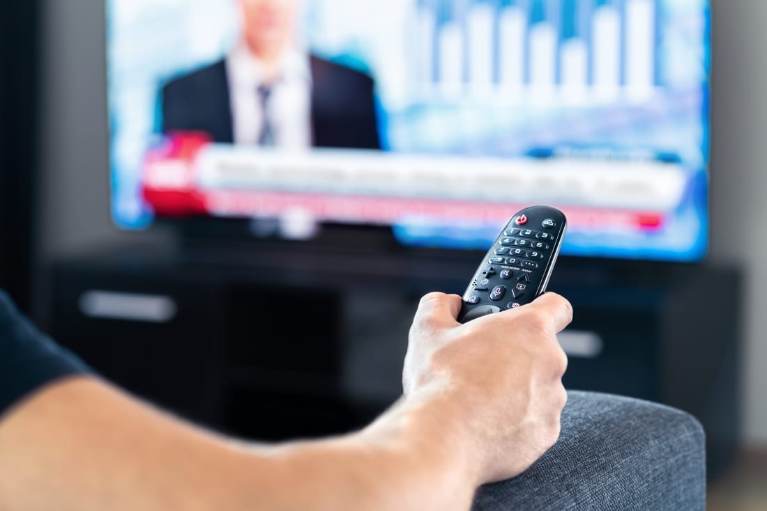 man watching TV holding remote control