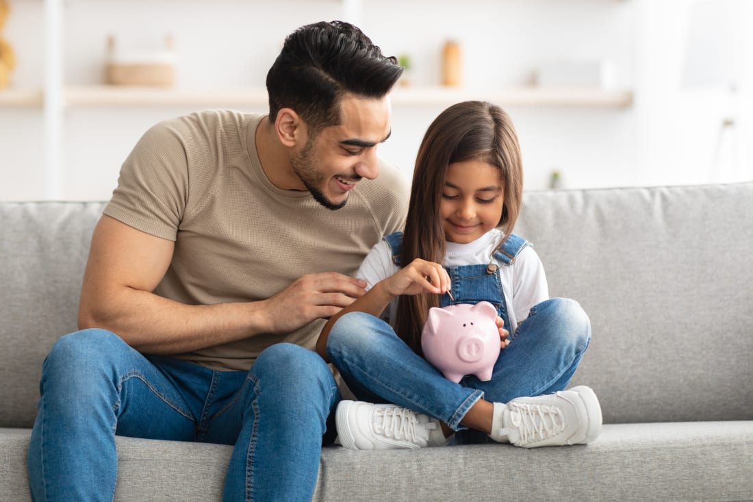 Dad and daughter adding money to piggy bank