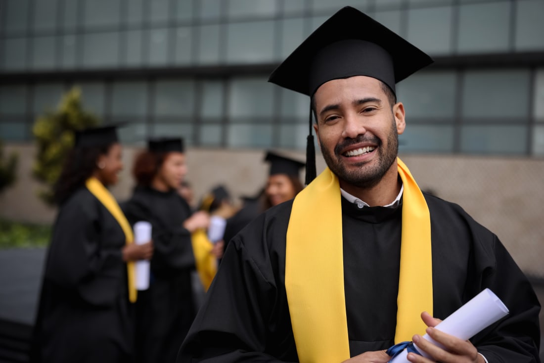 college graduate wearing cap and gown and holding a degree