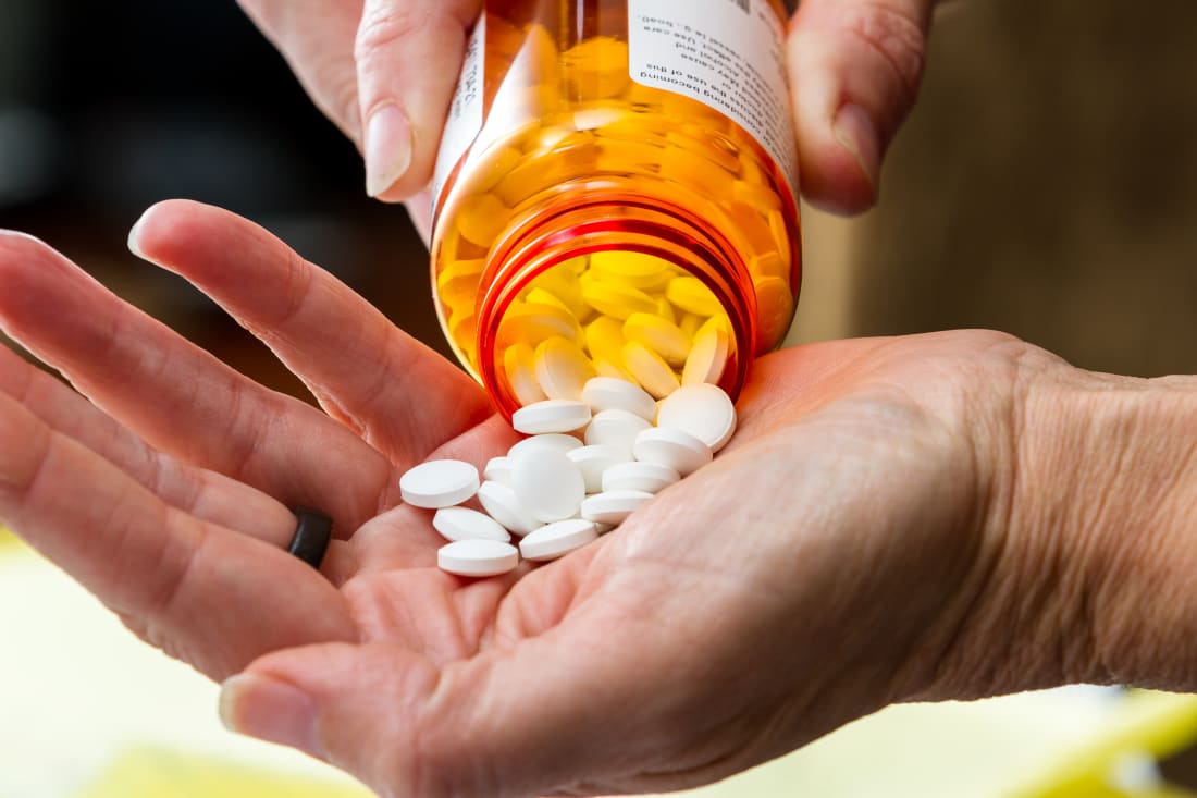 closeup of hand pouring pills from a prescription drug container 