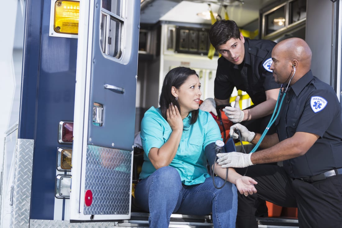 paramedics help patient on truck
