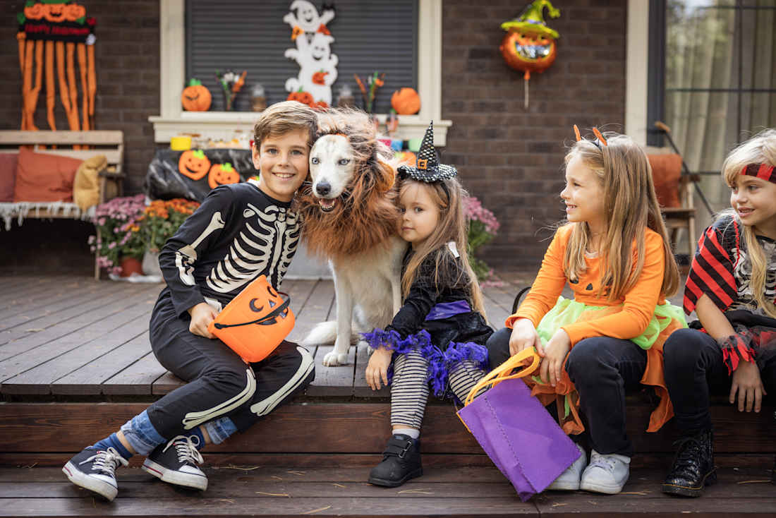 kids sitting on porch with Halloween costumes