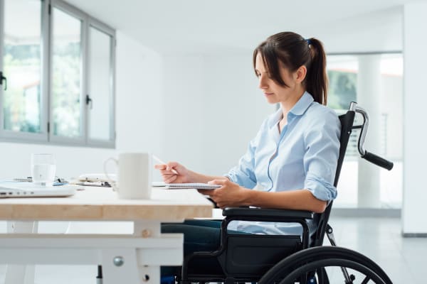 Confident disabled business woman in wheelchair working at office desk 