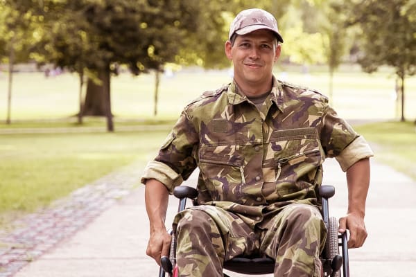 Happy disabled military man in wheelchair wearing camouflage uniform