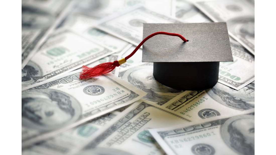 a miniature graduation cap on a pile of money