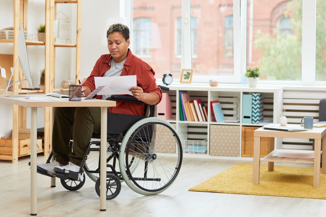 African American woman sitting in wheelchair and doing paperwork at office