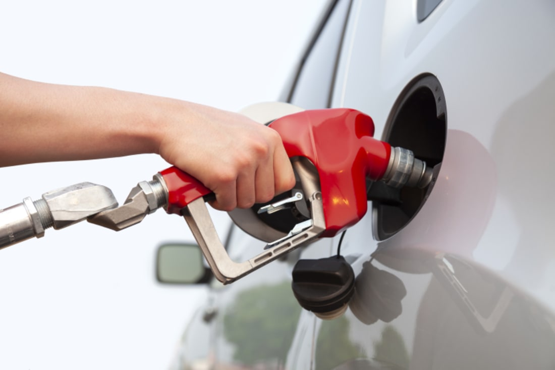 hand on the handle of gas pump while filling car's gas tank
