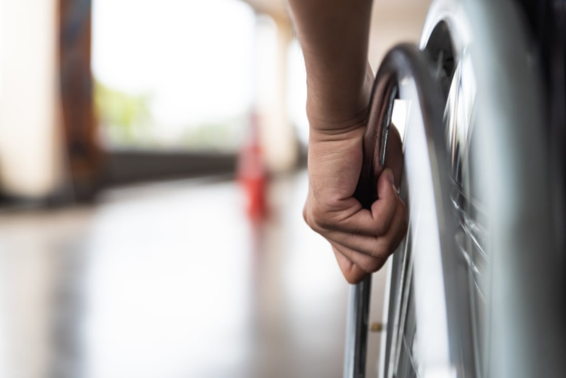 Close-up of man's hands on wheel of wheelchair