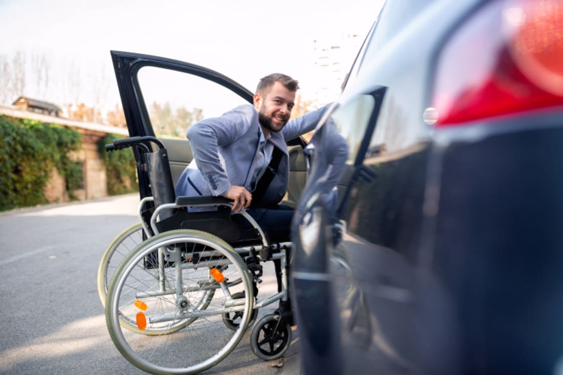 Handicapped man getting out of wheelchair and into car