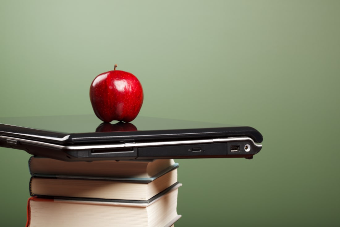 An apple on top of a laptop sitting on top of textbooks