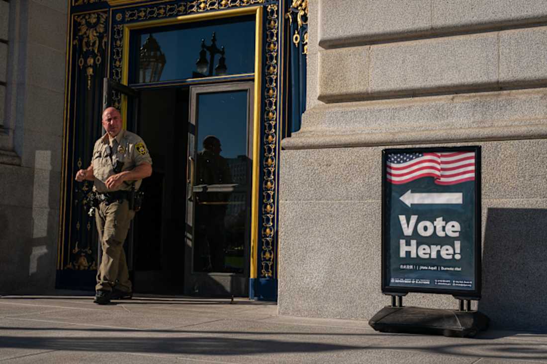 Police officer outside the entrance to a public building serving as a polling place during the election