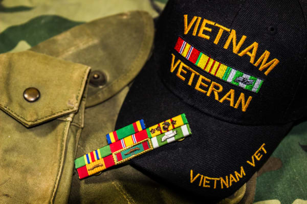 Vietnam veterans hat, service ribbons and pouches on camouflage uniform