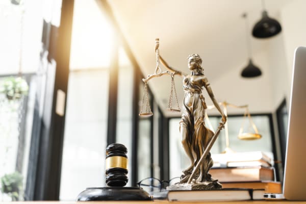 Statue of Justice on a desk next to gavel