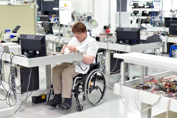Handicapped worker in a wheelchair assembling electronic components