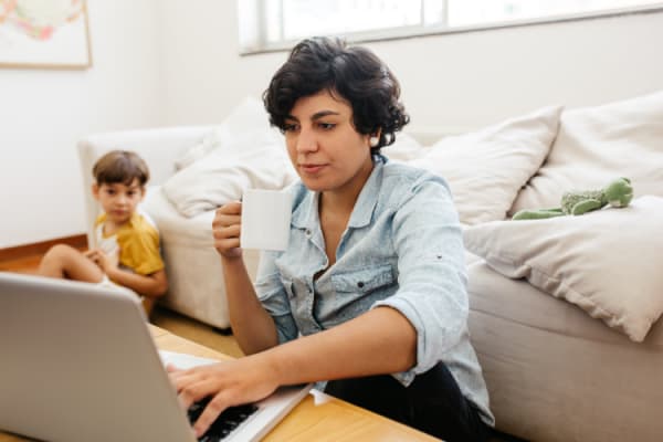 Mother busy working on laptop with her son sitting in background