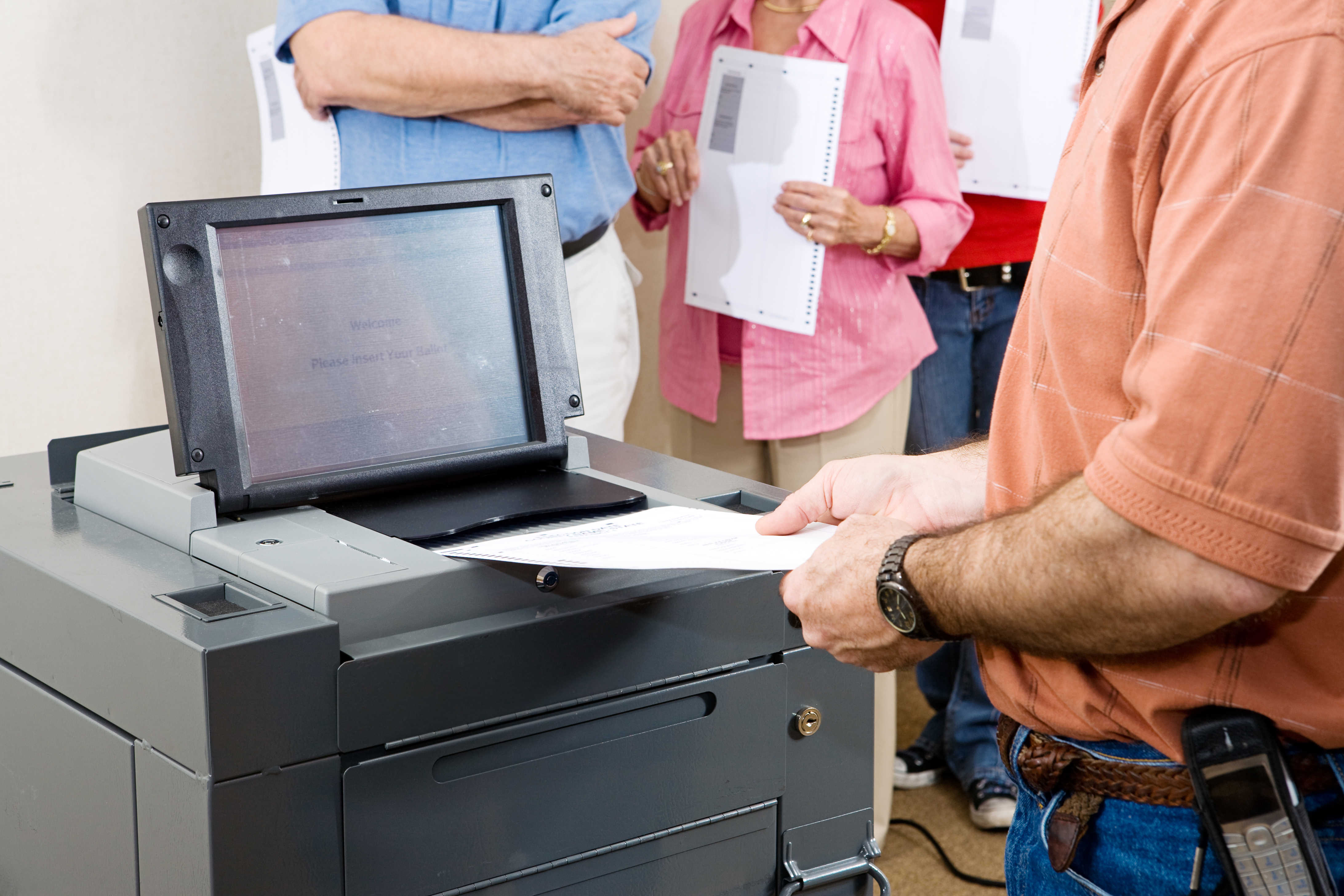 Man putting ballot into voting machine